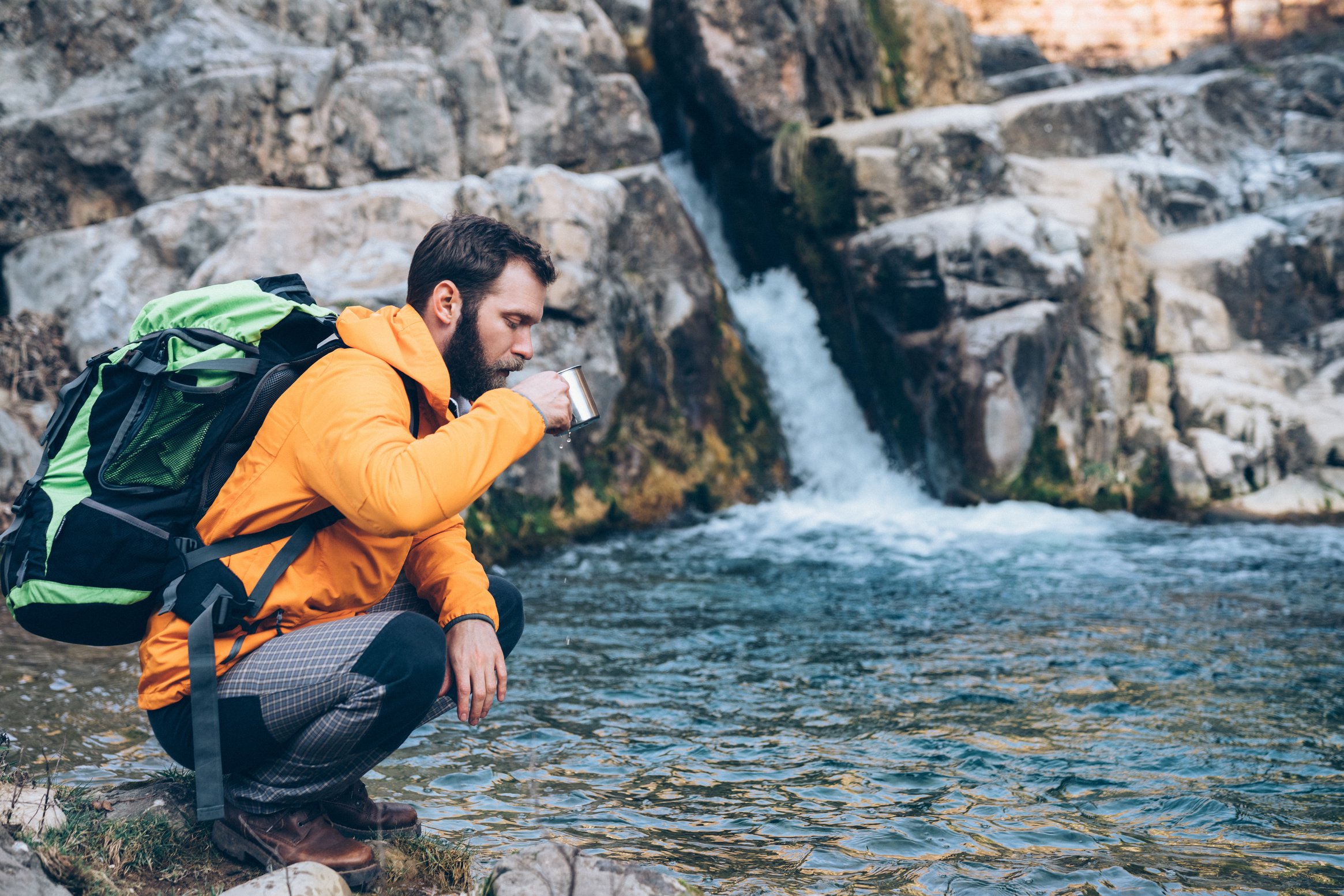 Man on hiking drinks water from a mug